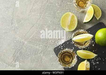 Tequila Schüsse mit Salz und Limette Schichten auf grauem Hintergrund Stockfoto
