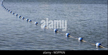 String von blauen und weißen Bojen auf ruhigen See Wasser. Als Grenzmarkierungen Schwimmbereich zu beschränken. Stockfoto