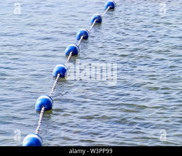 String von blauen und weißen Bojen auf ruhigen See Wasser. Als Grenzmarkierungen Schwimmbereich zu beschränken. Stockfoto