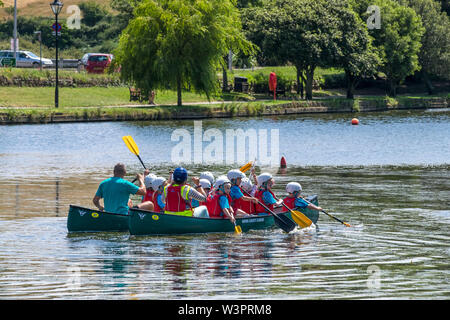 Grundschüler genießen einen freien Ausübung Aktivität Lektion, wie sie Spaß haben, Kanufahren auf trenance Garten See zum Bootfahren in Newquay in Cornwall. Stockfoto