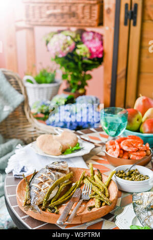 Gebratener Fisch auf einer Platte. Esstisch mit verschiedenen Speisen und Snacks. Meeresfrüchte und Gemüse. Sommer Mittagessen im Freien Stockfoto