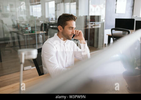 Junge Unternehmer sprechen über ein Handy in einem Büro Stockfoto