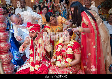 In der Nähe der Abschluss eines traditionellen hinduistischen Hochzeit, Familie Mitglieder der Beläge von der Braut & Bräutigam entfernen. In Queens, New York City. Stockfoto