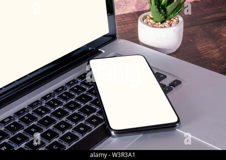 Smartphone weißen leeren Bildschirm auf Laptop Tastatur auf Holztisch mit liefert. Stockfoto