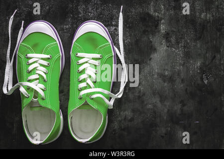 Blau - blaugrün - Grün - türkis Sneaker mit Ungebundener Schnürsenkel auf einem dunklen konkreten Hintergrund. Kopieren Sie Platz. Ansicht von oben Stockfoto