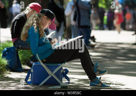 SAINT-Petersburg, Russland - Juni, 11 2014: hübsche Blondine jugendlich Zeichnung plain air Arbeit im Schatten der sonnigen Park. Stockfoto