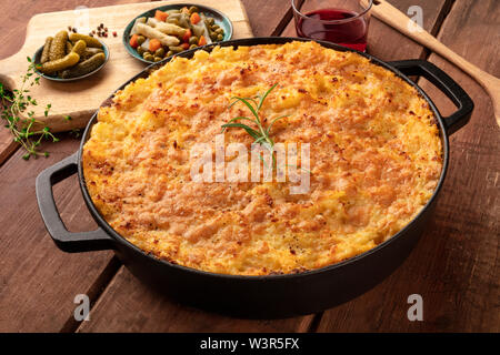 Shepherd's Pie in einem kochenden Topf mit Essiggurken, Kräuter, und Rotwein, auf einem dunklen Holzmöbeln im Landhausstil Hintergrund Stockfoto