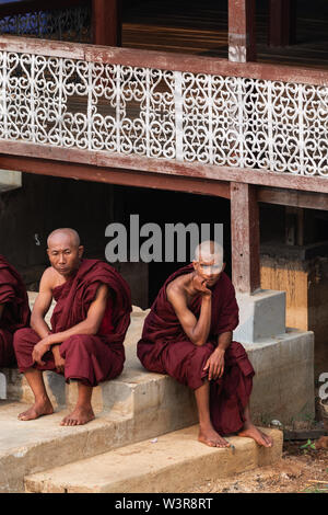 Maing Thauk, Myanmar - April 2019: Buddhistische Mönche sitzen auf einem Kloster Veranda am Inle See, traurige und nachdenkliche Stockfoto