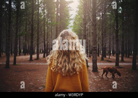 Blonde junge Frau mit ihrem Hund im Wald