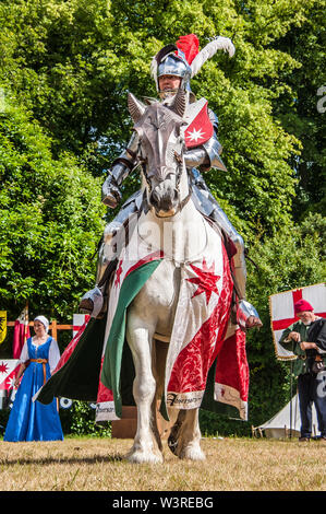 Eine gepanzerte Ritter auf seinem Ladegerät betritt die Arena während eine Historische Re-enactment am Turnier Woche in Arundel Castle, Foto © Julia Claxton Stockfoto