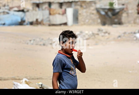 Khan Yunis, Gazastreifen, palästinensischen Gebiet. 17. Juli, 2019. Ein palästinensischer Junge isst Eis außerhalb seines Hauses während ein heißes Wetter Welle sitzt, in einem Slum am Rande von im Khan Yunis Flüchtlingslager im südlichen Gazastreifen am 17 Juli, 2019 Credit: Ashraf Amra/APA-Images/ZUMA Draht/Alamy leben Nachrichten Stockfoto