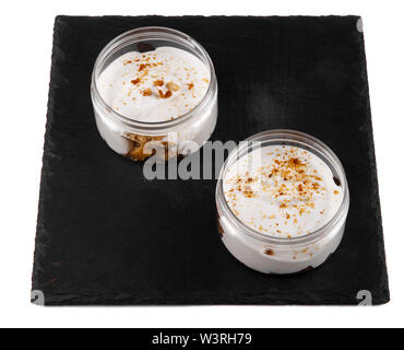 Honig cheesecake Dessert in einem Glas auf einen schwarzen Stein Platte auf weißem Hintergrund Stockfoto