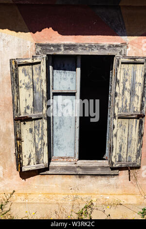 Außenfenster und gebleichtem Holz- Shutter Detail einer Verfallenen WW2 Gebäude, an der Klippe Rand; Baia Sardinia, Sardinien, Italien. Stockfoto