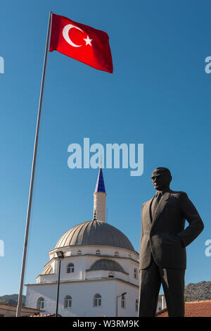 Die türkische Flagge oben eine Statue des ehemaligen Präsidenten M.K.Atatürk, der neben einer Moschee in Bozburun, die Türkei steht Stockfoto