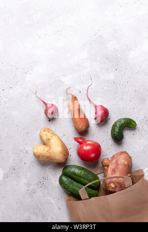 Satz Reifen hässlich Gemüse in Diagonalen von papiertüte verstreut auf grauem Beton Hintergrund. Stockfoto