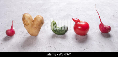 Fünf hässliche Gemüse stehen in Reihe auf grauem Beton Hintergrund. Stockfoto