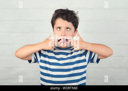 Unhöflich Kind einen gegen Ziegel Hintergrund Grimasse Stockfoto