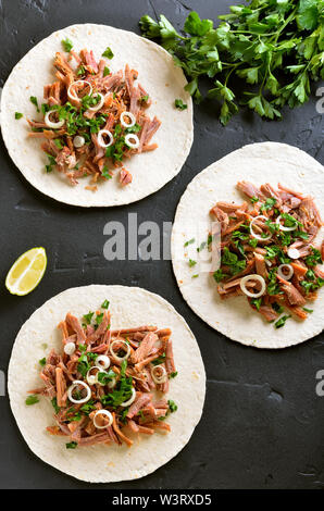 Zog Schweinefleisch soft Tacos auf schwarzem Stein. Ansicht von oben, flach Stockfoto