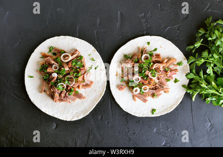 Zog Schweinefleisch soft Tacos auf schwarzem Stein. Ansicht von oben, flach Stockfoto