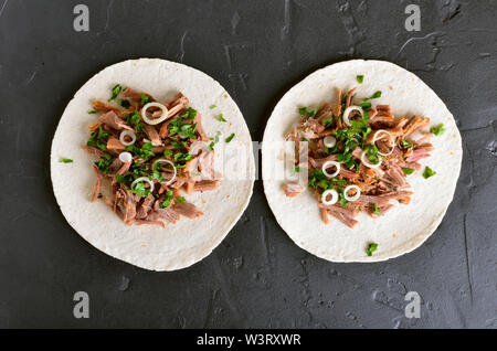 Zog Schweinefleisch soft Tacos auf schwarzem Stein. Ansicht von oben, flach Stockfoto