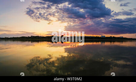 Wunderschöner Sonnenuntergang Panorama über die Stadt Horizont mit Reflexion über die ruhige See Wasser in einem stillen Sommerabend. Stockfoto