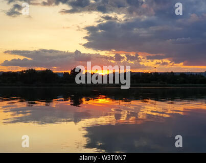 Schönen Sonnenuntergang über der Stadt Horizont mit Reflexion über die ruhige See Wasser in einem stillen Sommerabend. Stockfoto