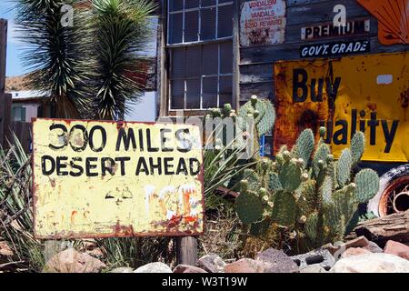 OATMAN (Arizona), USA - AUGUST 7. 2009: 300 KM WÜSTE AHEAD'-Schild mit Cactus vor der abgebrochenen Shop Stockfoto