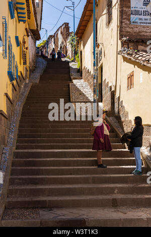 Zwei Frauen plaudern auf die Schritte, die man im modernen Kleid, das andere in traditioneller Kleidung in Cusco, Peru, Südamerika Stockfoto