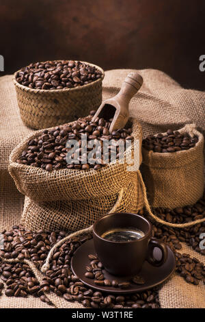 Tasse Kaffee im Vordergrund und Sack von Yuta mit gerösteten Kaffeebohnen Stockfoto