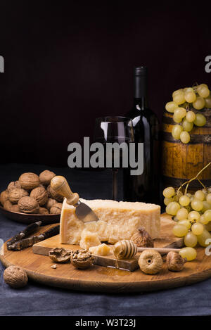 Holz Schneidebrett, auf dem es die gereiften Käse entsorgt, getrocknete Feigen, Nüsse und Wein Stockfoto