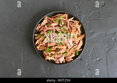 Langsam zog gekochte Schweinefleisch für Sandwiches mit Petersilie auf Teller. Ansicht von oben, flach Stockfoto