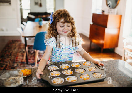 Junge Mädchen, dass Zinn von frischem Pfirsich Muffins im Ofen Stockfoto