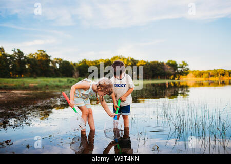 Junge Mädchen helfen jungen einen Fisch in seinem Netz fangen am See Stockfoto