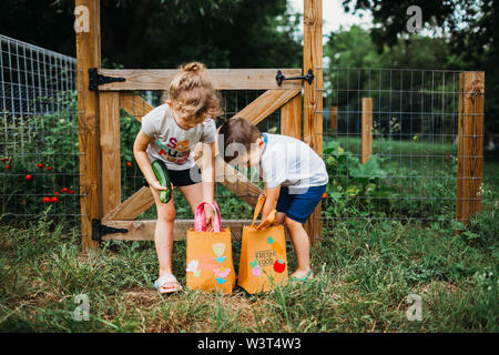 Jungen und Mädchen veggies in die Taschen von Hinterhof Garten Stockfoto