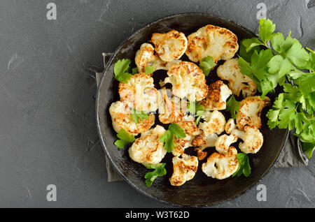 Vegetarisches Essen. Gebratener Blumenkohl auf die Platte über der schwarzen Hintergrund mit kopieren. Ansicht von oben, flach Stockfoto