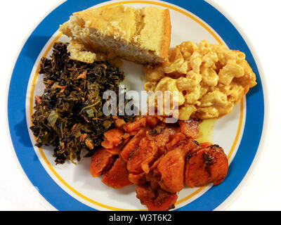 Eine Platte von Southern Comfort Essen in Amerika. Eine Umhüllung von Kale Grüns, kandierten Yamswurzeln, Makkaroni und Käse, und Maisbrot. Ansicht von oben. Stockfoto