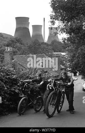 Jungs schieben ihre Räder auf Lincoln Hill, Ironbridge mit den Kühltürmen im Hintergrund. Stockfoto