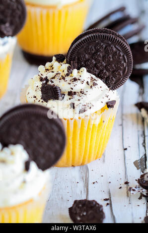 Schöne Vanille Cupcakes mit Zuckerglasur buttercream dekoriert mit Schokolade gefüllt Cookies. Selektiver Fokus mit unscharfem Hintergrund. Stockfoto