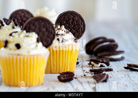 Schöne Vanille Cupcakes mit Zuckerglasur buttercream dekoriert mit Schokolade gefüllt Cookies. Selektiver Fokus mit unscharfem Hintergrund. Stockfoto