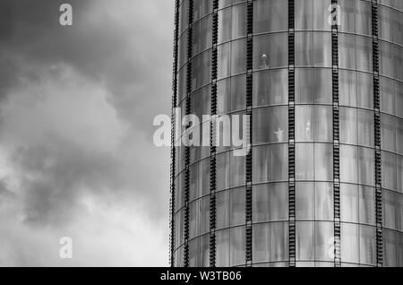 Schwarz-weiß Foto der Wolkenkratzer und ein dramatischer Himmel irgendwo in London. Die Brasil miniatur Statue von Jesus Christus ist in einem der w gesehen Stockfoto