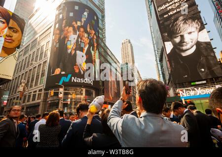 Mitarbeiter mit ihren Familien und Freunden sammeln an der riesigen Bildschirm an der Nasdaq Börse in Times Square in New York für das Debüt des DouYu International Holdings Ltd. Börsengang am Mittwoch, 17. Juli 2019. DouYu ist die größte live-Streaming Plattform in China und wird von Tencent Holdings Ltd. unterstützt die Bewertung der Unternehmen bei $ 3,73 Mrd. ist es die größte chinesische IPO im Jahr 2019. (© Richard B. Levine) Stockfoto