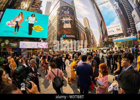 Mitarbeiter mit ihren Familien und Freunden sammeln an der riesigen Bildschirm an der Nasdaq Börse in Times Square in New York für das Debüt des DouYu International Holdings Ltd. Börsengang am Mittwoch, 17. Juli 2019. DouYu ist die größte live-Streaming Plattform in China und wird von Tencent Holdings Ltd. unterstützt die Bewertung der Unternehmen bei $ 3,73 Mrd. ist es die größte chinesische IPO im Jahr 2019. (© Richard B. Levine) Stockfoto