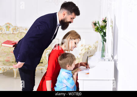 Eltern Elternschaft genießen, lehre Kind zu schreiben. Heimschule Konzept. Kid growthing in der Wohlfahrt. Vater peeking, während Mutter lehrt Sohn Stockfoto