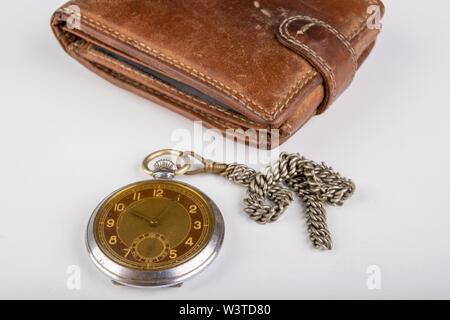 Lederetui und eine alte Uhr auf einem weißen Tisch. Persönliche Dokumente in Leder. Hellen Hintergrund. Stockfoto