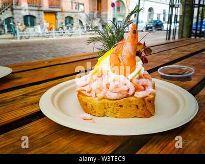 Frisches Sandwich mit Garnelen und Zitrone im dänischen Stil, es ist eine köstliche Mahlzeit. Es ist auf einem Schild an einem Holztisch in Kopenhagen serviert. Stockfoto