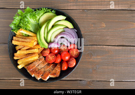 Gegrillte geschnitten Schweinesteak mit Kartoffeln, Tomaten, Avocados in der Pfanne. Ansicht von oben, flach Stockfoto