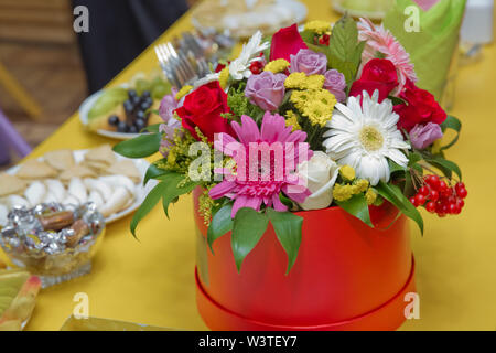 Romantisch rot, weiß, gelb, lila Rosen in roter Geschenkbox das Logo auf einem gelben Hintergrund Frühling zu legen kommt, den internationalen Frauentag. Bea Stockfoto