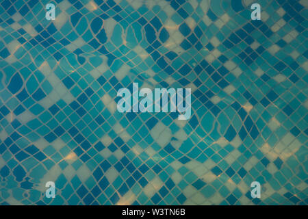 Das Mosaik ist dunkelblau, Blau und Weiß auf dem Boden des Pools. Brechung der Sonnenstrahlen Stockfoto