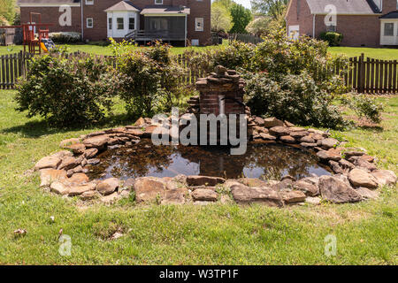 Einen koi Teich von Steinplatten, stagnierenden und ungepflegt in einem Garten umgeben. USA. Stockfoto