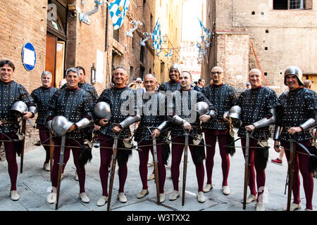 Männer in historischen mittelalterlichen Kostümen Linie bis zur Vorbereitung für die Parade des Palio durch die Straßen von Siena, Italien Stockfoto